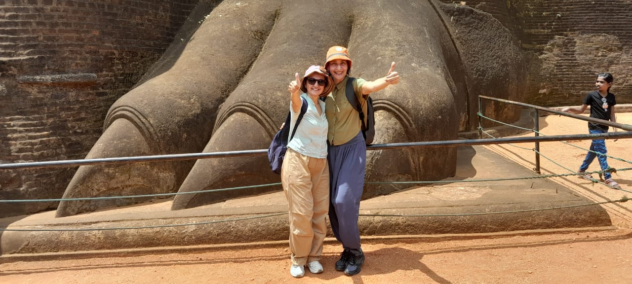 Two guests beside the giant stone lion's paw at the foot of Sigiriya Rock