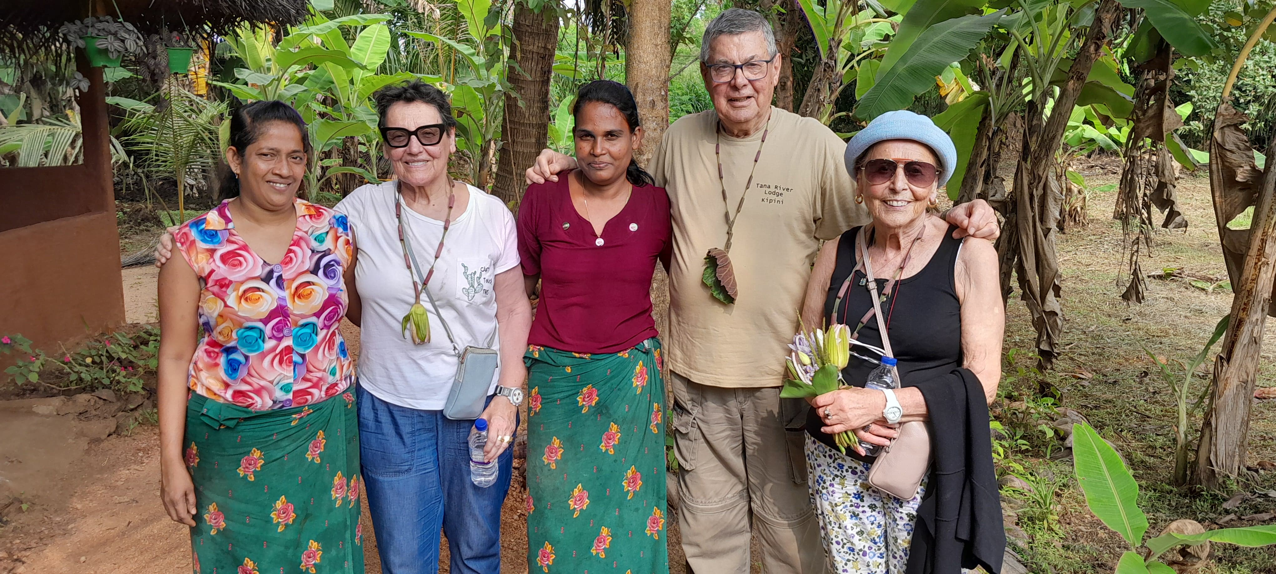 Guests posing with their village hosts under green trees